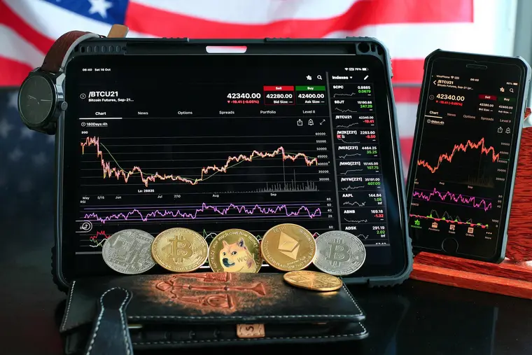 Physical bitcoin token resting on a screen showing candlestick price charts