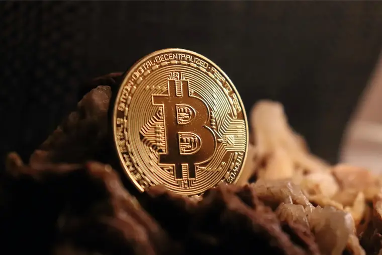A physical commemorative bitcoin coin resting on a dark textured surface