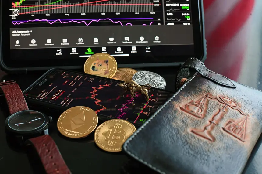 A smartphone showing a crypto trading app beside a laptop with market data